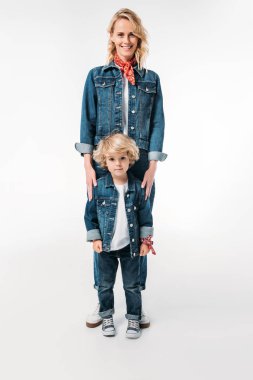 Anne ve oğlu ayakta gülümseyen ve üzerinde beyaz izole kamera bakıyor