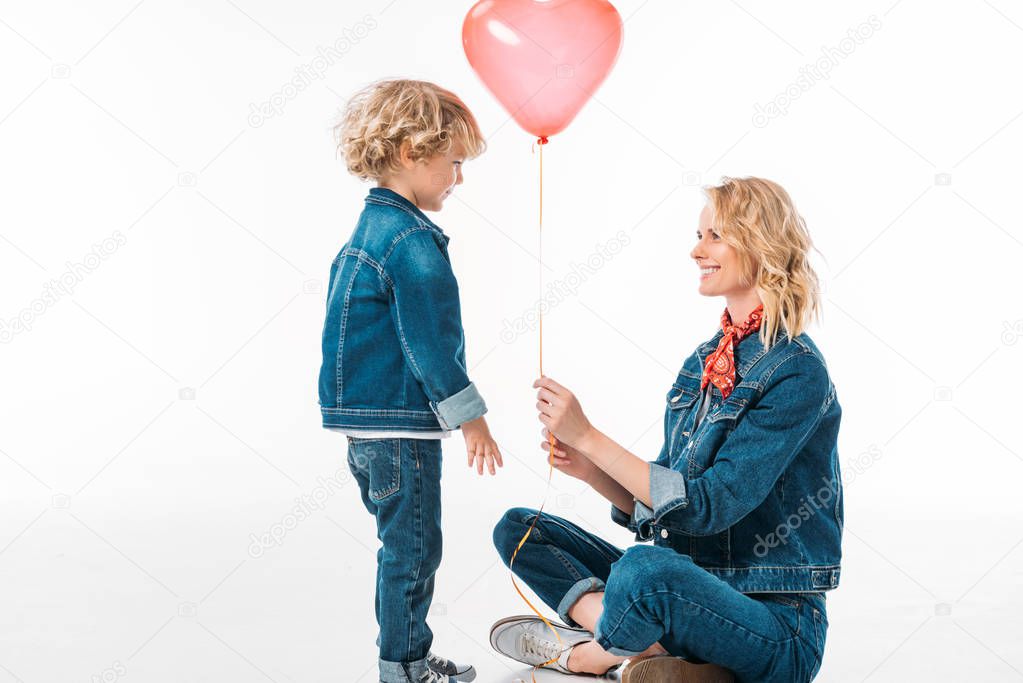 son presenting red balloon to mother isolated on white