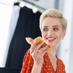 Close up portrait of smiling woman holding slice of pizza