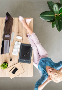 şık kadın teleworker ayaklı bilgisayar, akıllı telefon ve grafik tablet evde masada oturan havai görünümü 