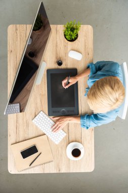 kadın Freelancer grafik tablet fincan kahve, smartphone ve evde bilgisayar ile masada çalışma office üstten görünüm 