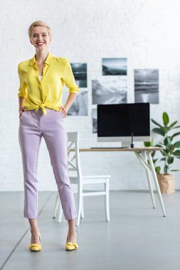 şık gülümseyen iş kadını elleri ceplerinde office kameraya bakarak 