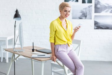 grafik tablet ve ev ofis bilgisayarı ile tablo yakınındaki Smartphone kullanarak gülümseyen kadın serbest meslek 