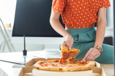 kadın Freelancer kutusunu bilgisayar ile masada pizza dilimi alarak resim kırpılmış 