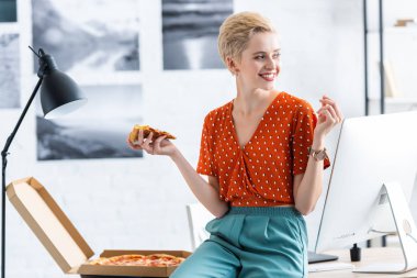 masada oturan ve Genel müdürlükte pizza yemek gülümseyen kadın serbest meslek 