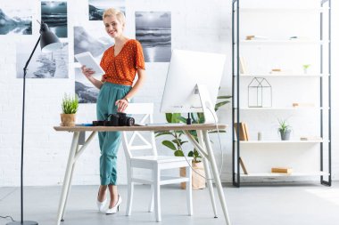 şık kadın fotoğrafçı ev ofis bilgisayarı ve fotoğraf kamera ile dijital tablet yakınındaki tablo kullanma 