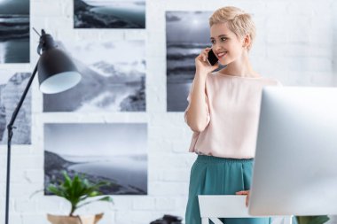 smartphone tuğla duvar fotoğrafları ile önünde konuşurken mutlu kadın fotoğrafçı 