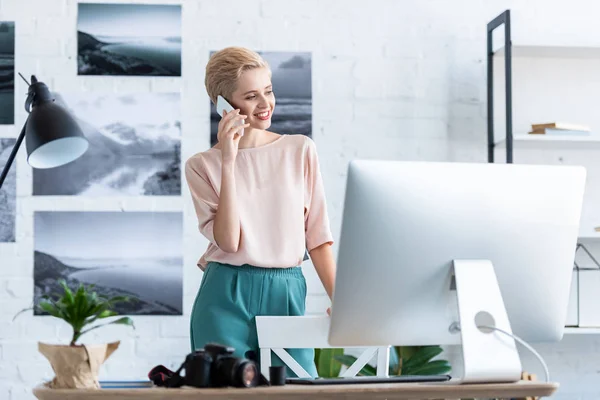 Smiling Female Photographer Talking Smartphone Table Photo Camera Computer Home — Stock Photo, Image