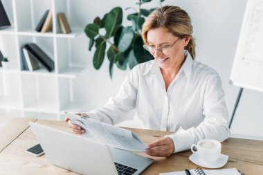 çekici işkadını okuma gazete laptop Office ile masada gülümseyen
