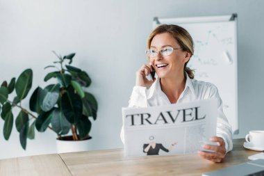 Smartphone ile konuşmak ve seyahat gazete ofisinde tutan çekici işkadını gülümseyen