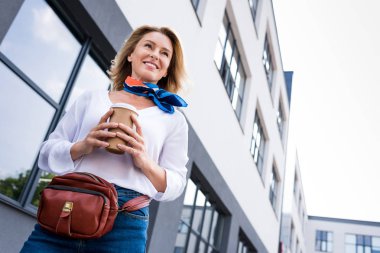 low angle view of beautiful woman walking with disposable coffee cup on street  clipart
