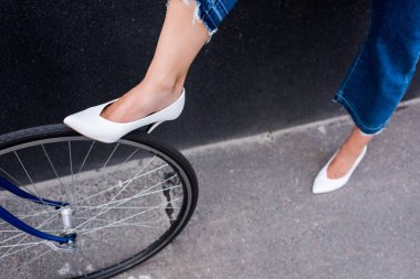 kadının Beyaz Ayakkabı Caddesi üzerinde bisiklet tekerleği dokunmadan kırpılmış görüntü 