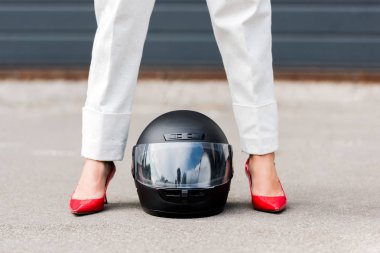 cropped image of woman in red shoes standing near motorcycle helmet on street  clipart