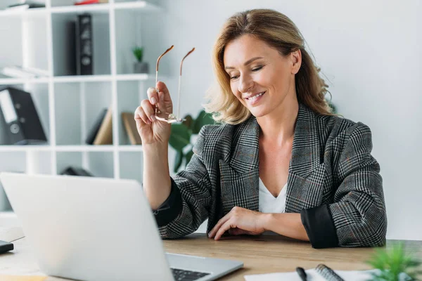 Atrakcyjna Kobieta Interesu Trzyma Okulary Patrząc Laptopie Biurze — Darmowe zdjęcie stockowe