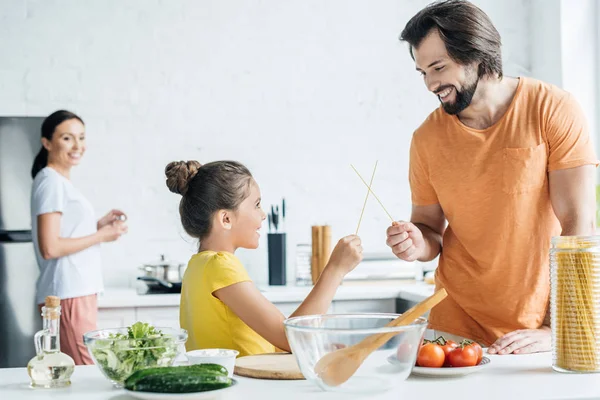 Padre Hija Jugando Con Palillos Mientras Madre Pie Borrosa Fondo — Foto de stock gratis