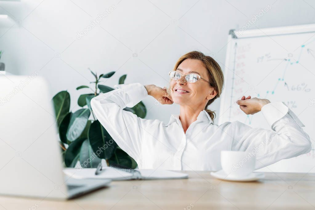 attractive businesswoman stretching at table in office