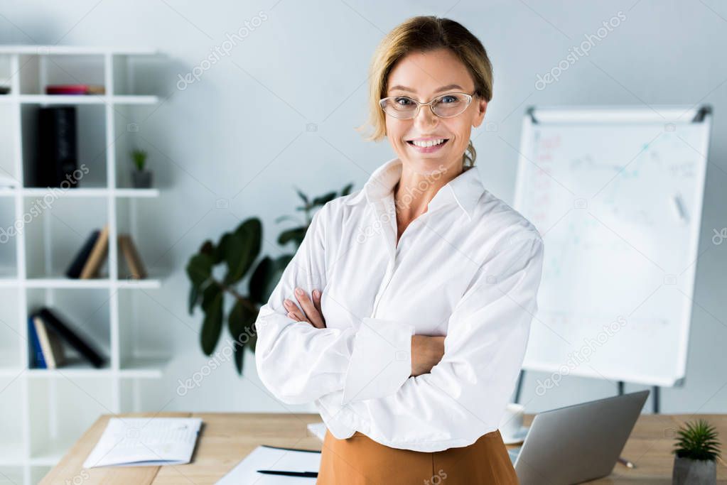 beautiful businesswoman standing with crossed arms in office