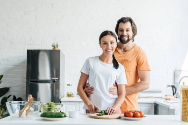 gülümseyen yakışıklı karısı o salata birlikte mutfağa hazırlanması sırasında kucaklayan