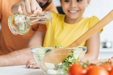 Baba ve kızı salata bir kase içine zeytin yağ boşaltma