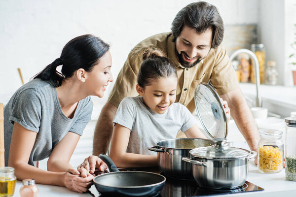 smiling young family cooking together at kitchen