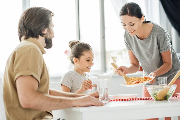 美味しい朝食はキッチンで夫と娘を持つ若い母親の笑みを浮かべてください — ストック写真