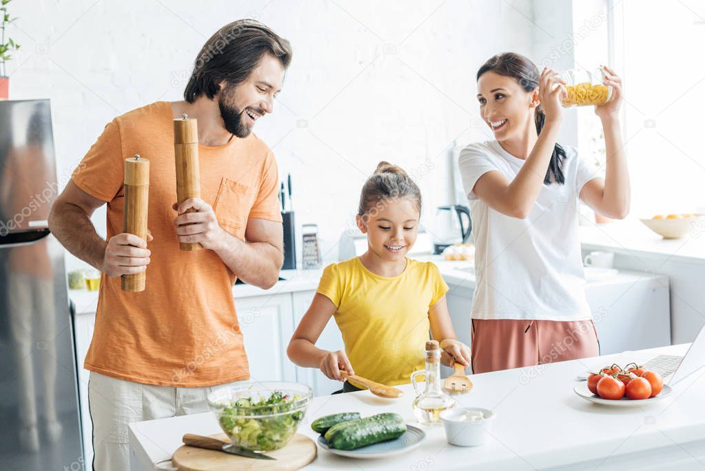 beautiful young family playing music with kitchenware and having fun at kitchen