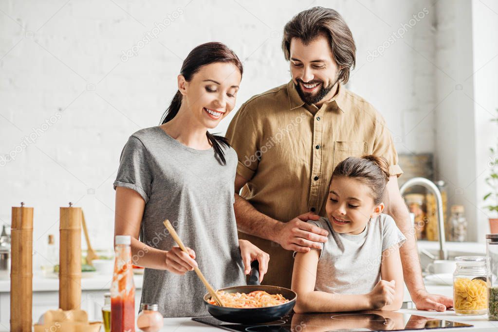 beautiful family with little daughter cooking omelet at kitchen