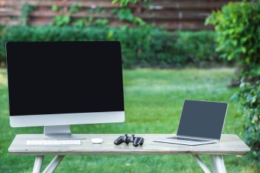 joystick, bilgisayar ve laptop açık havada masada boş ekranlar ile seçici odak 