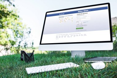 ders kitabı ve bilgisayarın açık havada çimenlerin üzerinde Web sitesi facebook ile seçici odak 