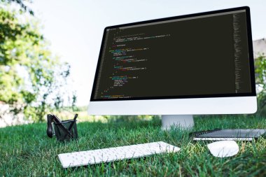selective focus of computer with programming language code on grass outdoors clipart