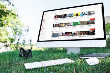 ders kitabı ve bilgisayarın açık havada çimenlerin üzerinde youtube Web sitesi ile seçici odak 