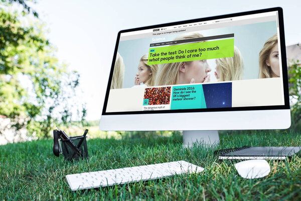 selective focus of textbook and computer with bbc science website on grass outdoors 