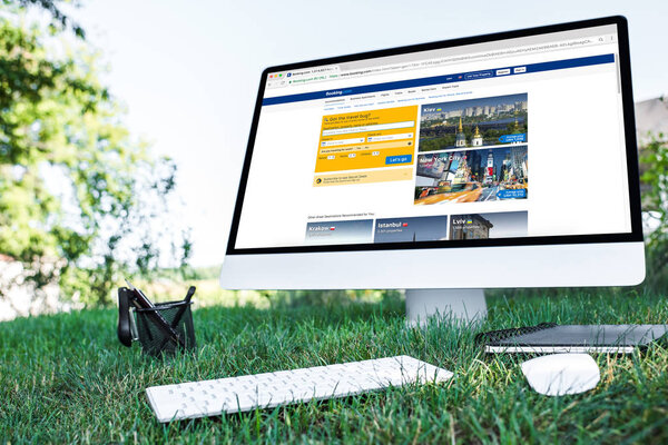 selective focus of textbook and computer with booking.com website on grass outdoors 