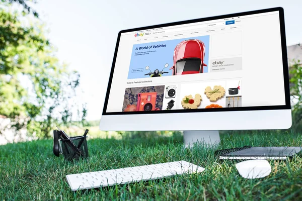 教科书与计算机的选择性聚焦与 Ebay 网站在草坪上的户外活动 — 图库照片
