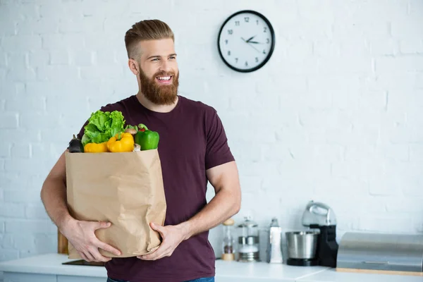 Bonito Sorrindo Jovem Segurando Saco Papel Com Legumes Frescos Olhando — Fotografia de Stock