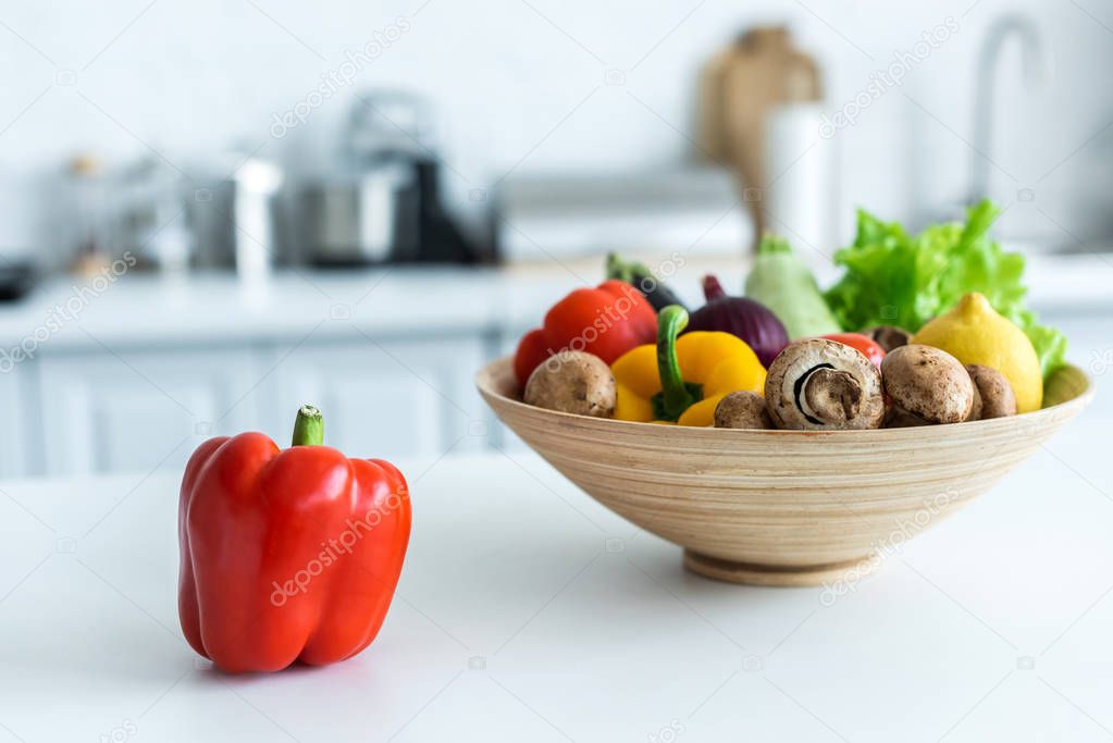 close-up view of bell pepper and bowl with fresh vegetables on kitchen table