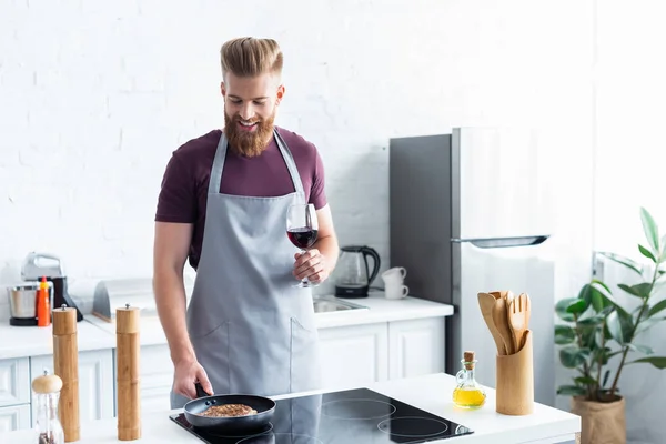 Smiling Young Man Apron Holding Glass Red Wine While Cooking — Stock Photo, Image