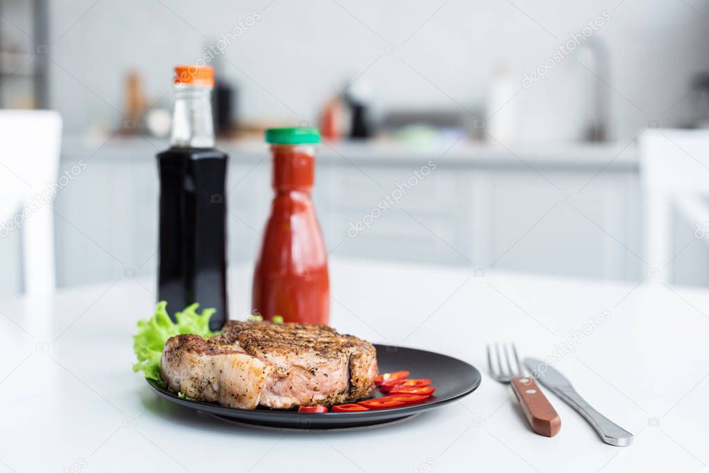 delicious grilled steak, sauces and fork with knife on table