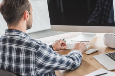 arkadan görünüşü genç programcı işyerinde masaüstü bilgisayar kullanarak