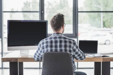 arkadan görünüşü genç programcı dizüstü bilgisayar ve masaüstü bilgisayar ile çalışma