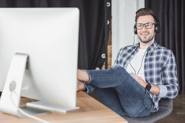 Jovem Sorridente Fones Ouvido Óculos Olhando Para Computador Desktop — Fotografia de Stock