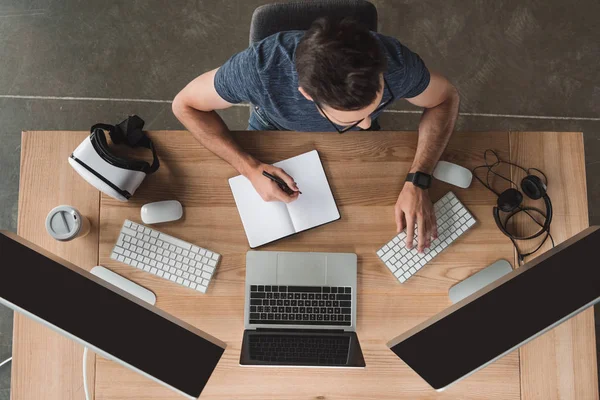 Overhead View Young Programmer Taking Notes Notebook Using Computers Workplace — Stock Photo, Image