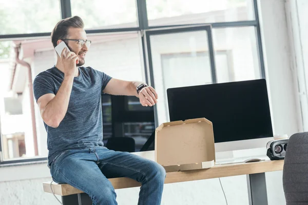 Knappe Jonge Programmeur Brillen Praten Door Smartphone Zittend Tafel Met — Stockfoto