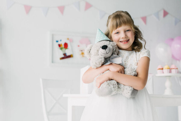 счастливый ребенок с плюшевым медведем в конусе
