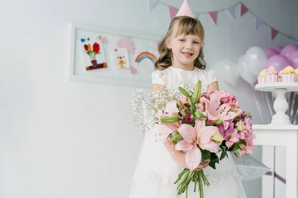 Smiling Birthday Child Cone Looking Camera Holding Bouquet Lilies — Free Stock Photo