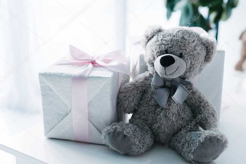 selective focus of teddy bear with gift boxes on table 