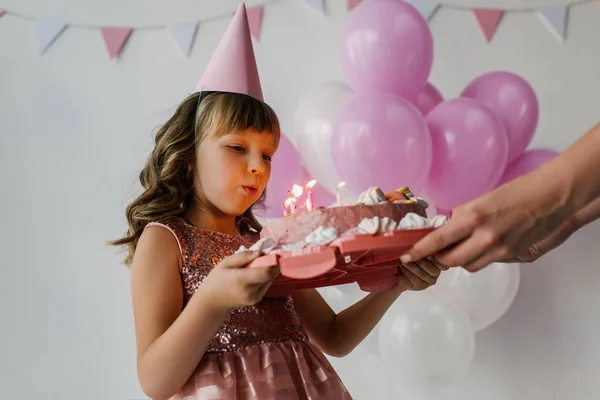 誕生日ケーキ子供ろうそくを吹きながら保持している母親のトリミングされた画像 — ストック写真