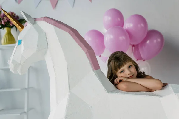 stock image little child sitting with decorative unicorn and bunch of pink balloons 