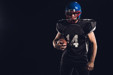 young american football player with ball looking at camera isolated on black clipart