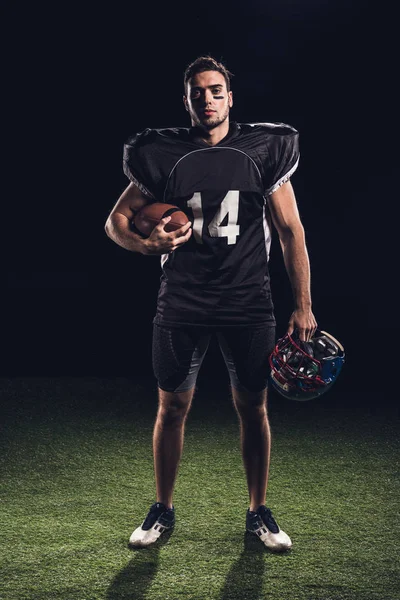 Confiado Jugador Fútbol Americano Uniforme Negro Con Casco Pelota Mirando — Foto de stock gratis